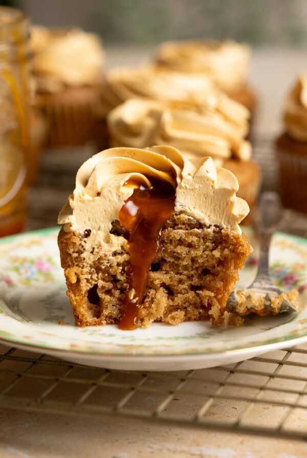 Caramel is running down a half cut caramel apple cupcake.