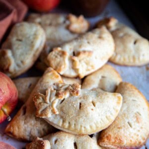 Apple hand pies piled on a baking sheet