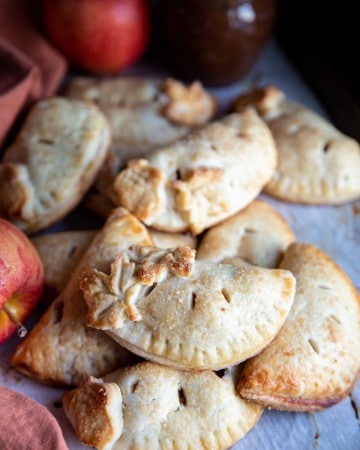 Apple hand pies piled on a baking sheet