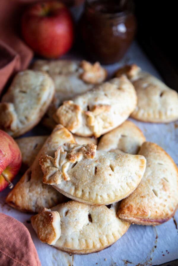 Apple hand pies piled on a baking sheet