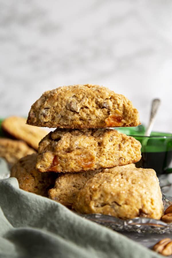 Two persimmon scones stacked on a plate of scones.