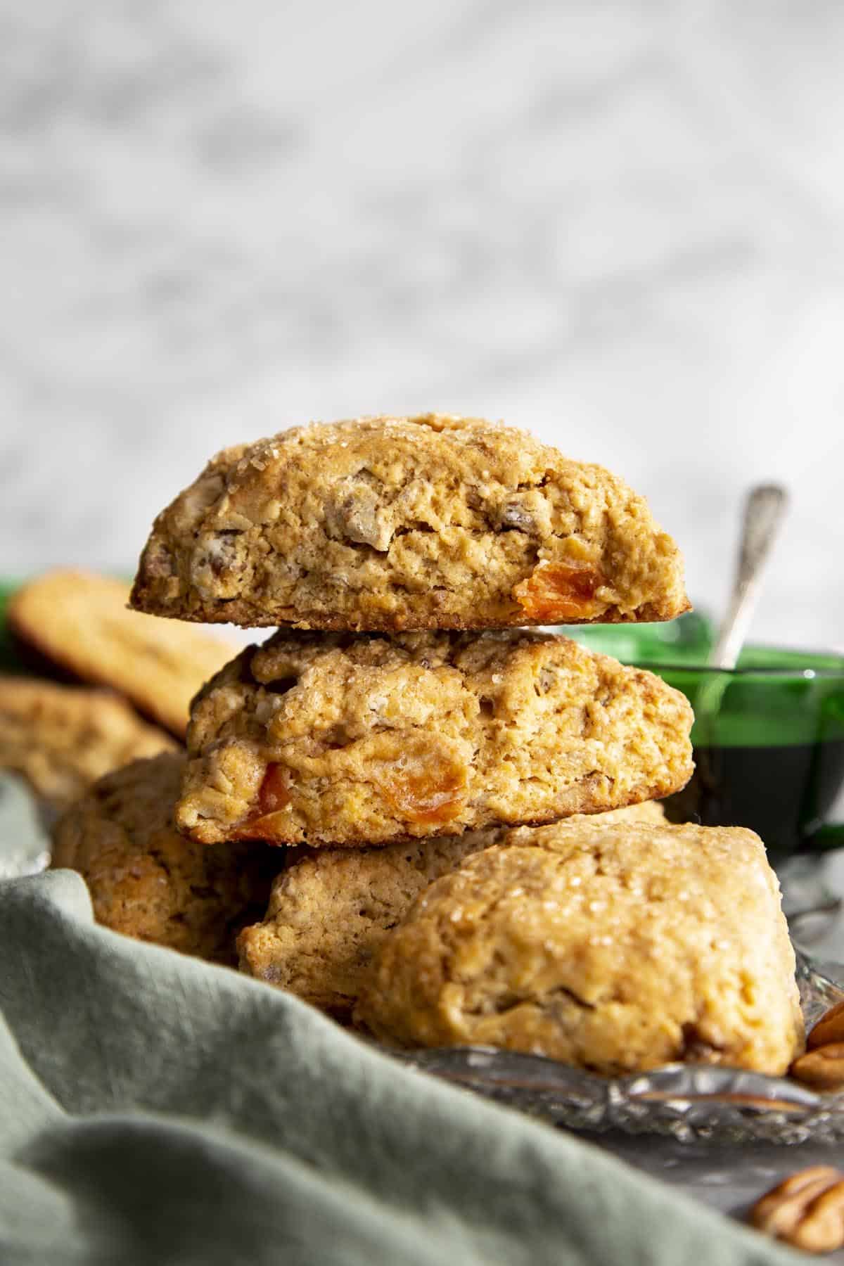 Cardamom Persimmon Pecan Scones Two persimmon scones stacked on a plate of scones.