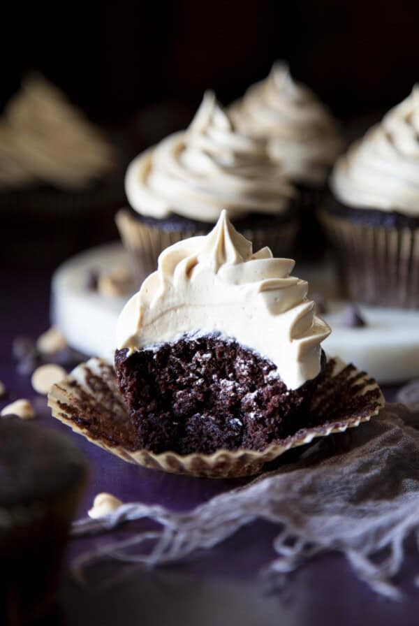 A chocolate cupcake with peanut butter frosting, with a bite taken out of it.