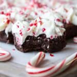 Festive chocolate brownies with peppermint on a cutting board.