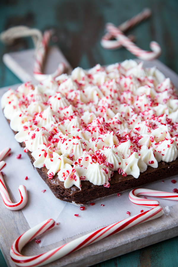 Peppermint brownies on a cutting board with candy canes