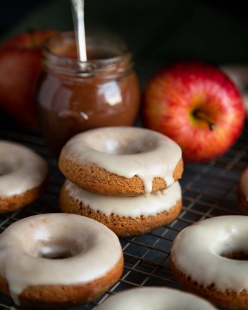 Glazed baked donuts on a wire rack with a jar of apple butter