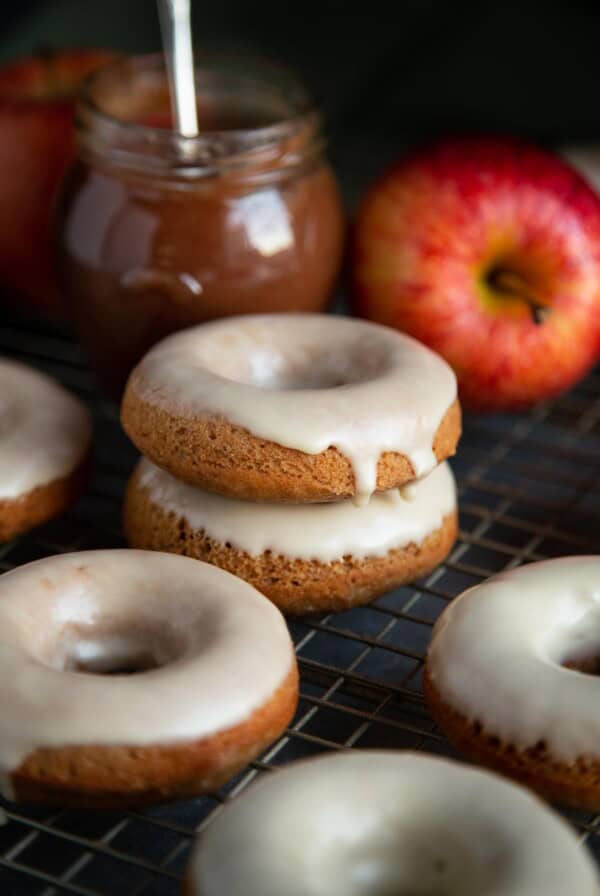 Glazed baked donuts on a wire rack with a jar of apple butter