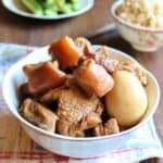 Vietnamese Braised Pork with Egg in a bowl, a rice bowl is in the back along with a plate of cucumber.
