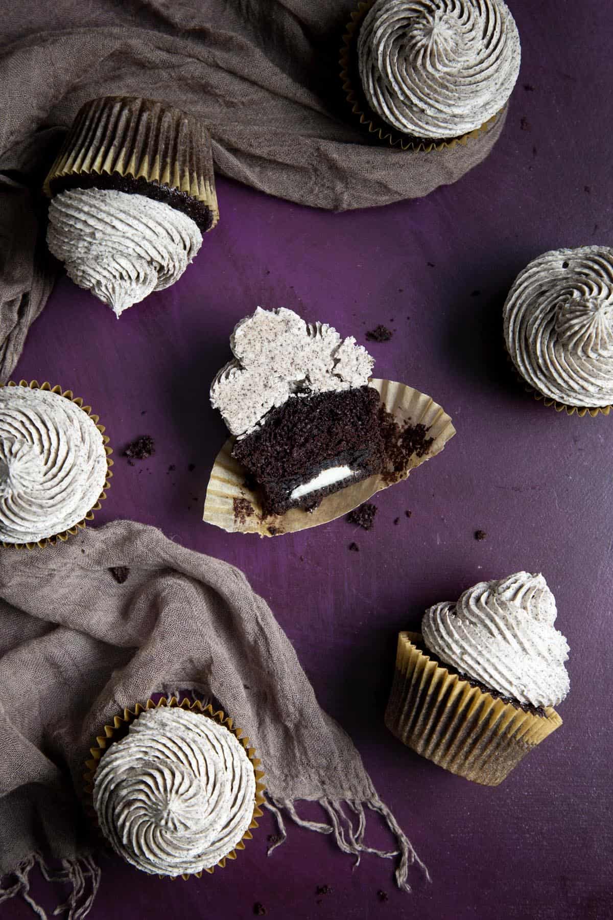A chocolate Oreo cupcake cut in half revealing the whole Oreo in the middle.