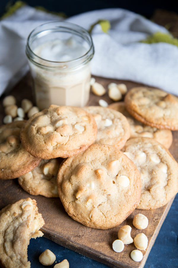 A pile of white chocolate macadamia nut cookies on a wooden board