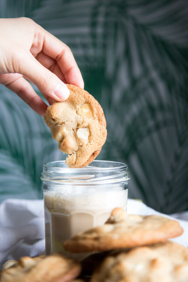Dipping a piece of white chocolate macadamia nut cookie into a cup of latte