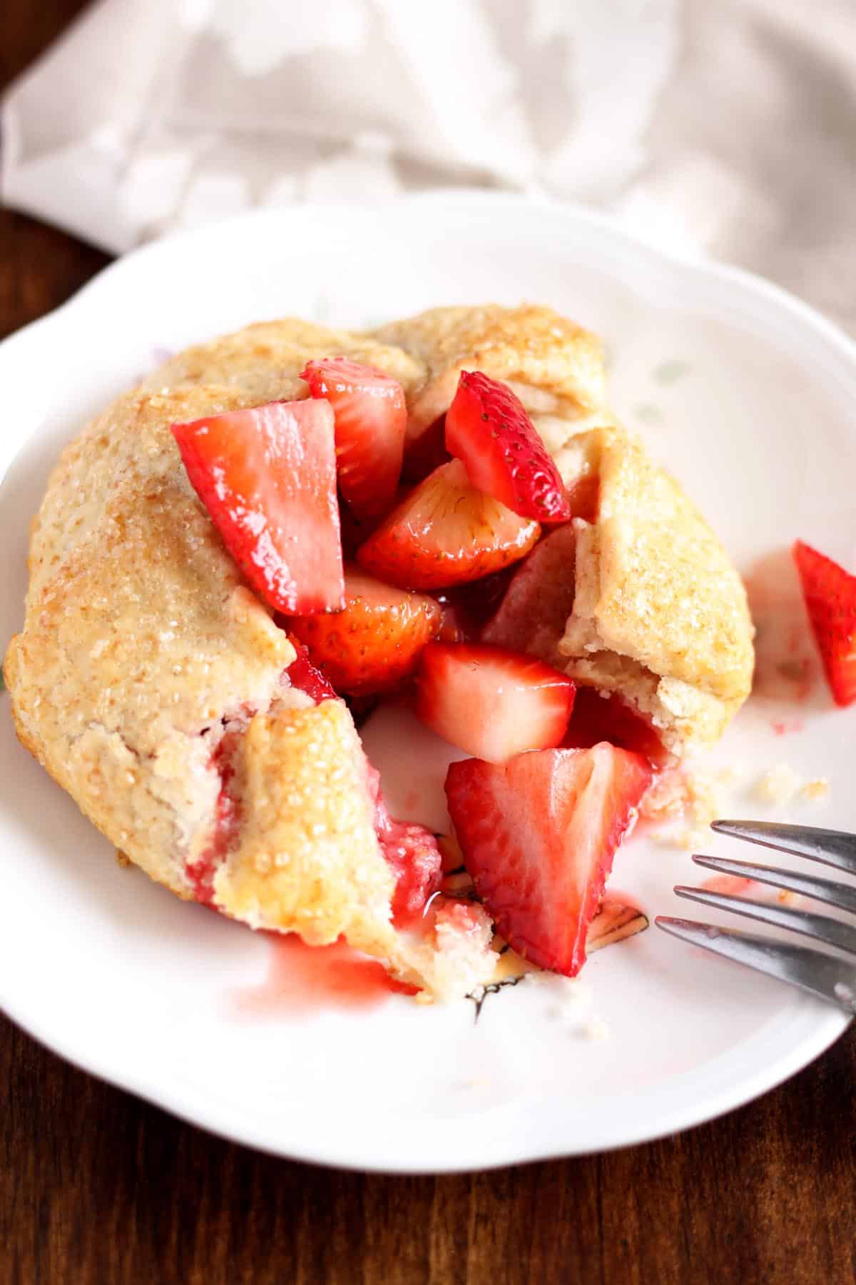 A strawberry galette on a plate being cut into.