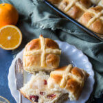 Orange cranberry hot cross buns with butter on a plate