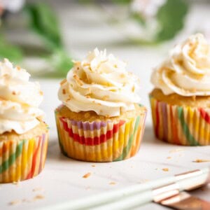 Three pina colada cupcakes lined up on a white marble surface.