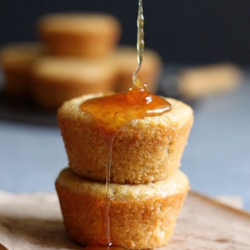 A stack of two sweet cornbread muffins being drizzled with honey