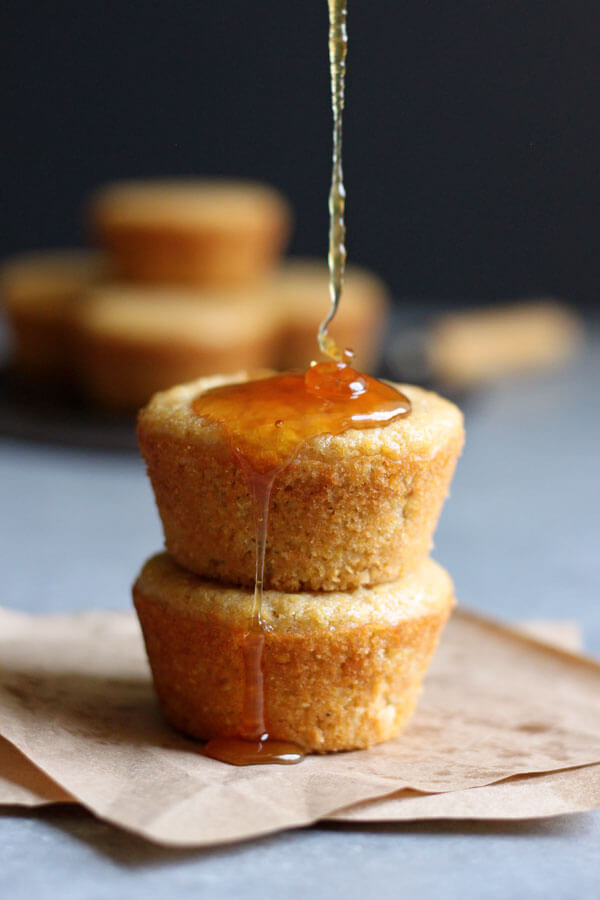 A stack of two sweet cornbread muffins being drizzled with honey
