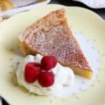 A slice of custard pie on a plate with whipped cream and raspberries.