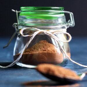 Pumpkin pie spice in a jar with a spoon of spice in front of it.