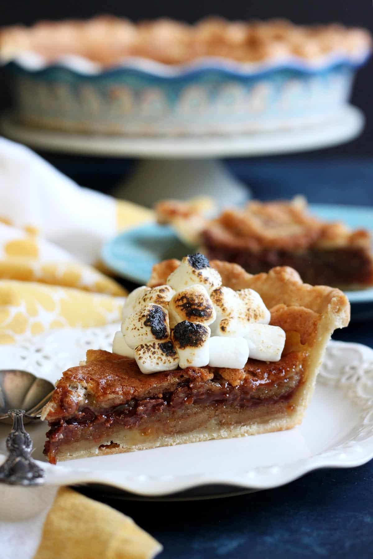 This S’mores Bomb Pie tastes like campfire s’mores on steroid. It is an intensely decadent dessert that will blow your mind! | wildwildwhisk.com