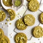Matcha white chocolate cookies spread over a table top with parchment paper.