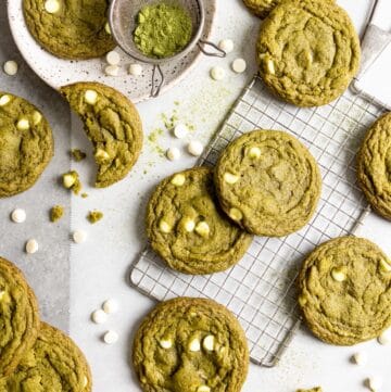 Matcha white chocolate cookies spread over a table top with parchment paper.