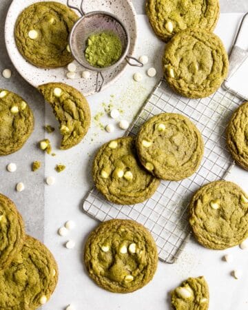 Matcha white chocolate cookies spread over a table top with parchment paper.