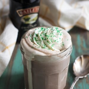 Baileys Irish cream hot chocolate with whipped cream spilling over in a glass jar.