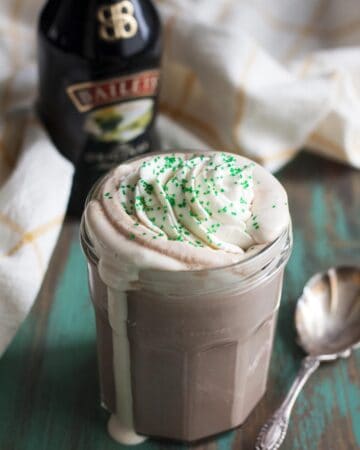 Irish cream hot chocolate with whipped cream spilling over in a mug