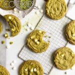 Matcha white chocolate cookies spread over a table top with parchment paper, one has a bite taken out.