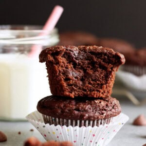 A stack of two Chocolate Coconut Yogurt Muffins, a bite was taken out of the top one
