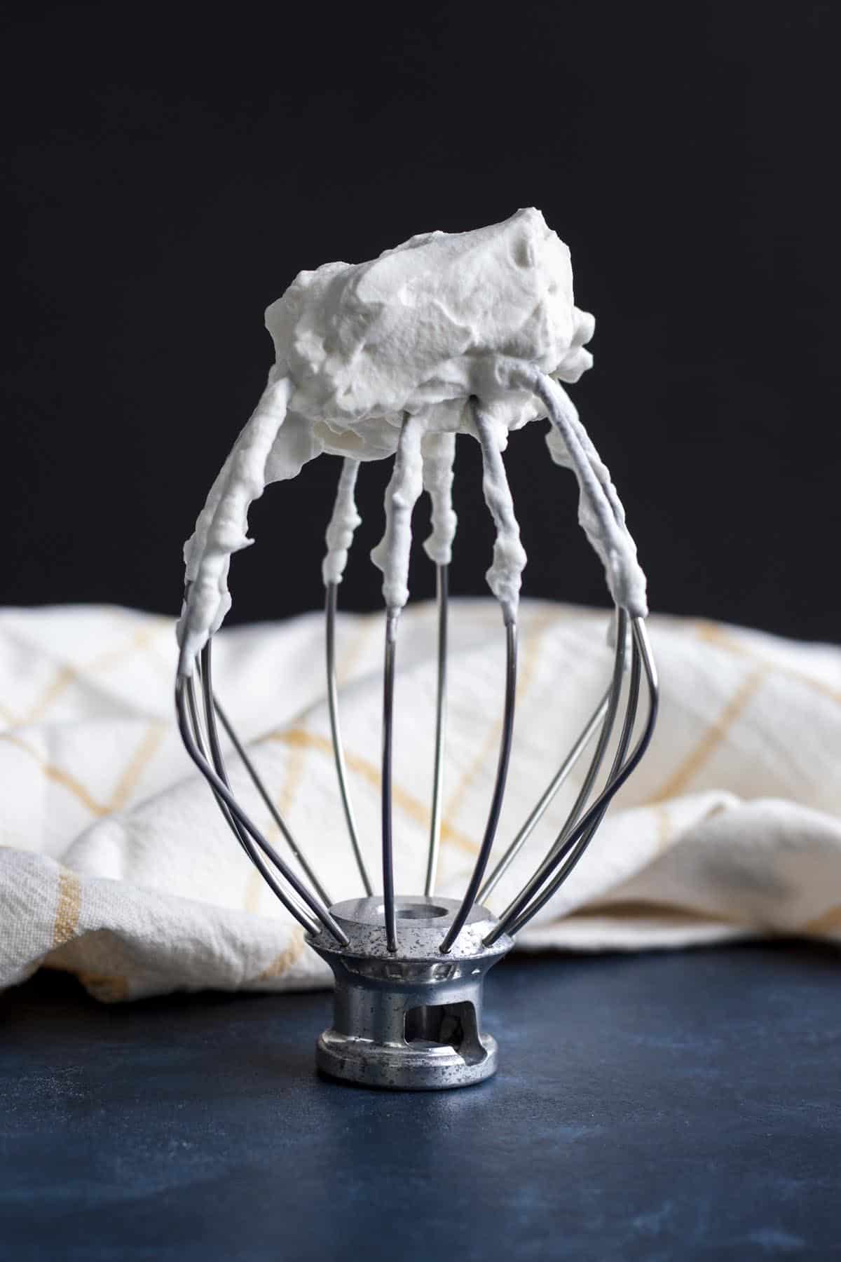 Homemade whipped cream whipped until stiff peaks, on a wire whip.