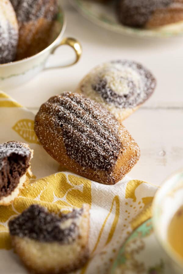 A couple chocolate and vanilla marble madeleines lying on a white table top.