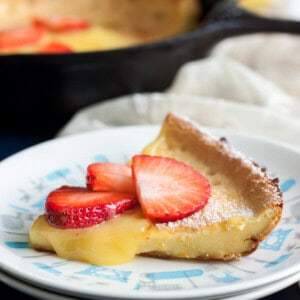A slice of Lemon Dutch Baby with lemon curd dripping on the side