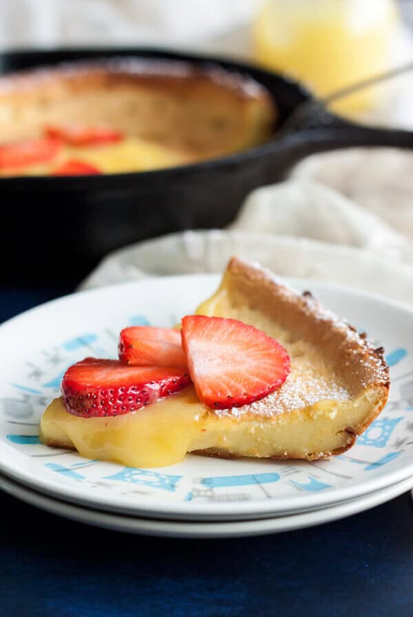 A slice of Lemon Dutch Baby with lemon curd dripping on the side