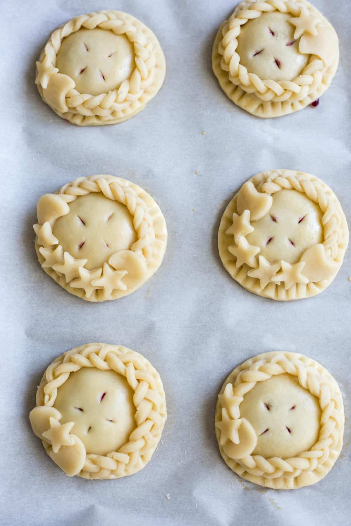Unbaked hand pies with braided and cutout decorations.