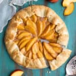 A peach galette on a green table top, a slice is cut out.