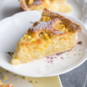 A slice of coconut pineapple tart on a plate resting on top of two other plates.