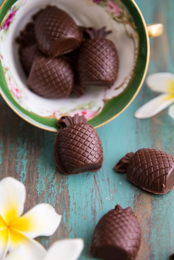 Pineapple Truffles falling out of a tea cup on a green table top.