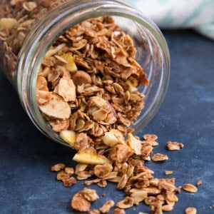 A jar of coconut granola on its side with granola spilling out of it.