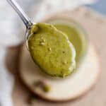 The image focuses on a spoonful of homemade pistachio butter.