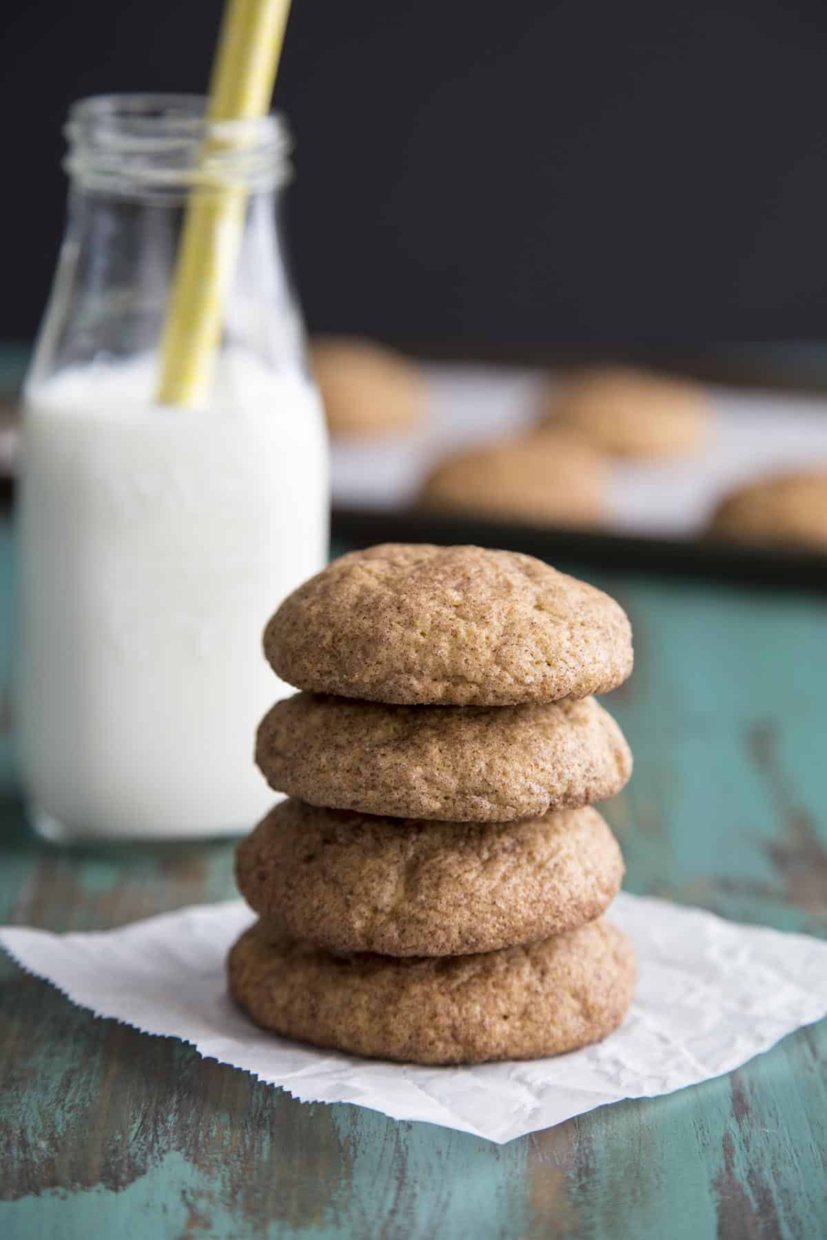 A stack of pumpkin snickerdoodle cookies with a bottle of milk in the back.