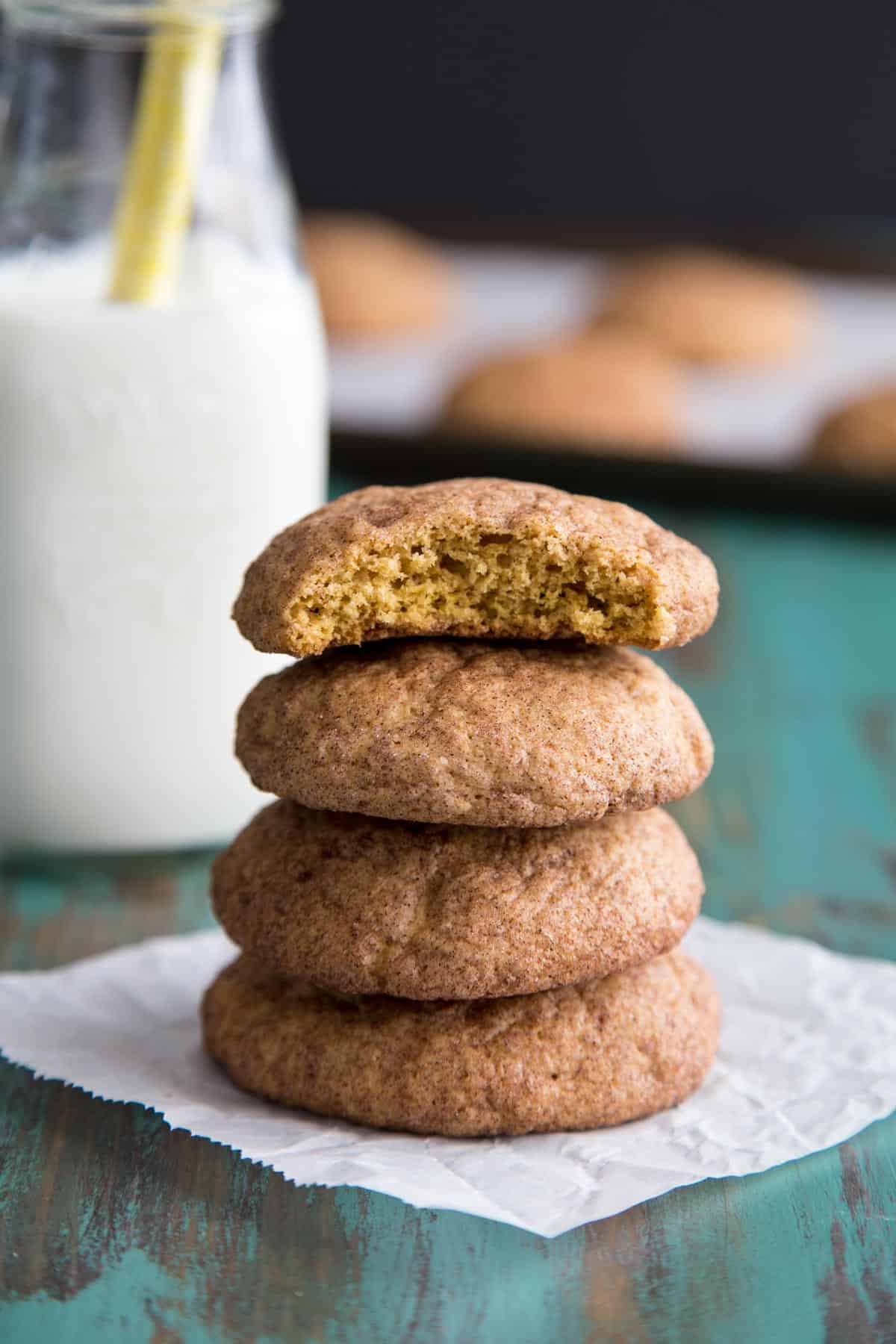 A stack of pumpkin snickerdoodle cookies with the top one half eaten.