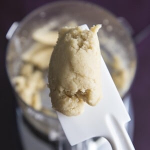 A spatula holding a piece of almond paste just made in a food processor.