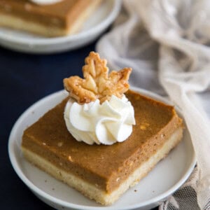Pumpkin Pie Shortbread Bars garnished with whipped cream and a pie crust maple leaf