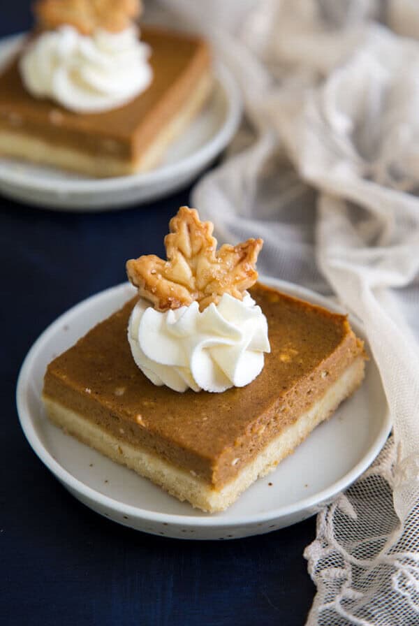 Pumpkin Pie Shortbread Bars garnished with whipped cream and a pie crust maple leaf