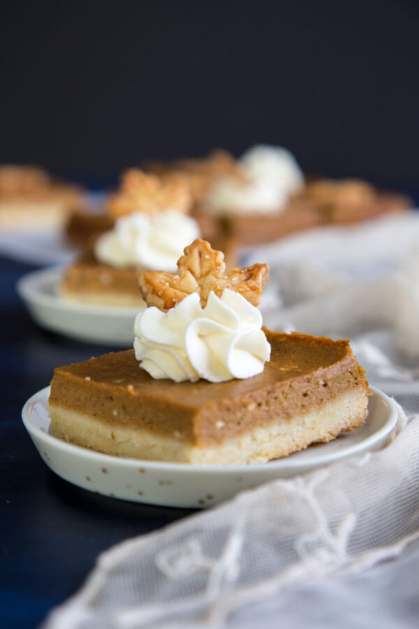 Pumpkin Pie Shortbread Bars garnished with whipped cream and a pie crust maple leaf