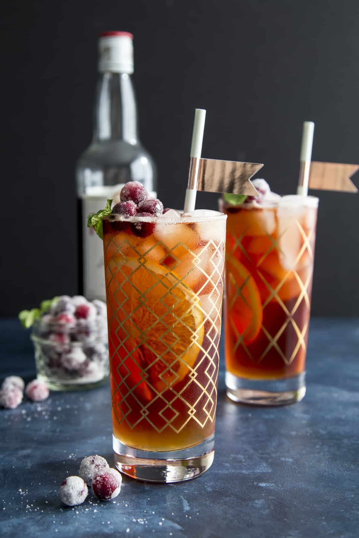 Cranberry Pimm's Cup is an easy and refreshing holiday cocktail made with Pimm's No. 1, apple cider, sparkling cranberry juice and garnished with sugared cranberries. #wildwildwhisk #pimmsno1 #pimmscup #cranberrypimmscup #sugaredcranberries Two Cranberry Pimm's Cup cocktails in highball glasses.