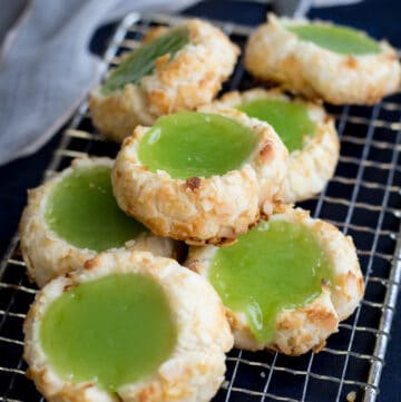 A pile of pandan cookies on a silver wire rack with a white towel in the background.