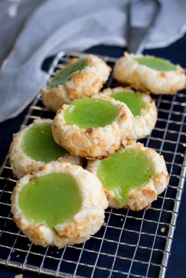 A pile of pandan cookies on a silver wire rack with a white towel in the background.