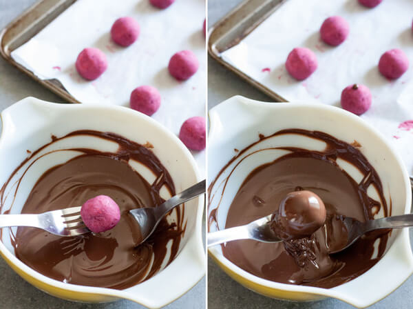 Dipping raspberry truffle balls into melted chocolate